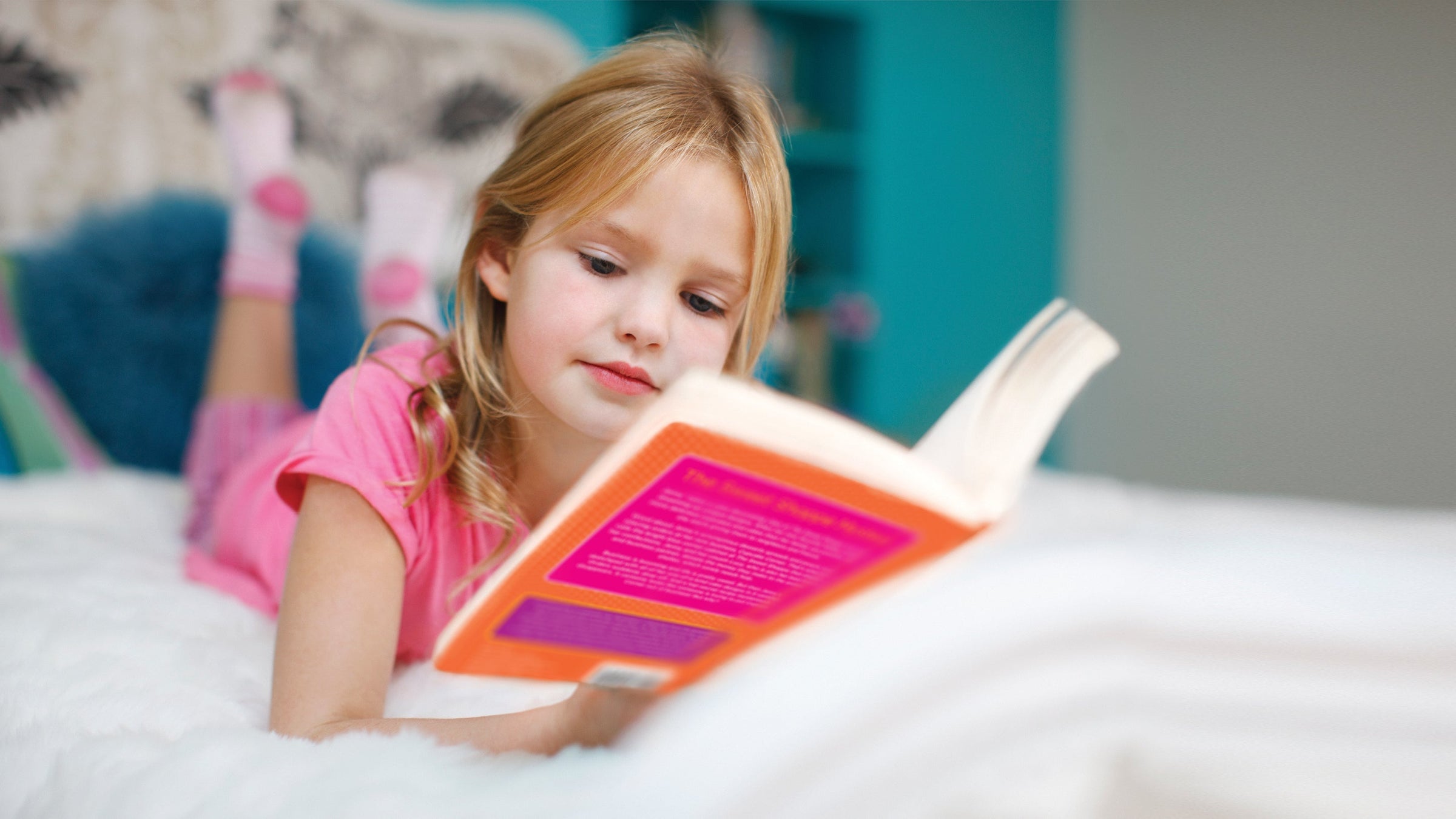 Young Girl reading an Our Generation book in bed